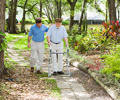 Elderly man with walker and caregiver